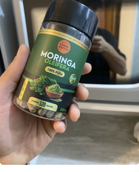 Cliente segurando o pote de Moringa 100% Pura